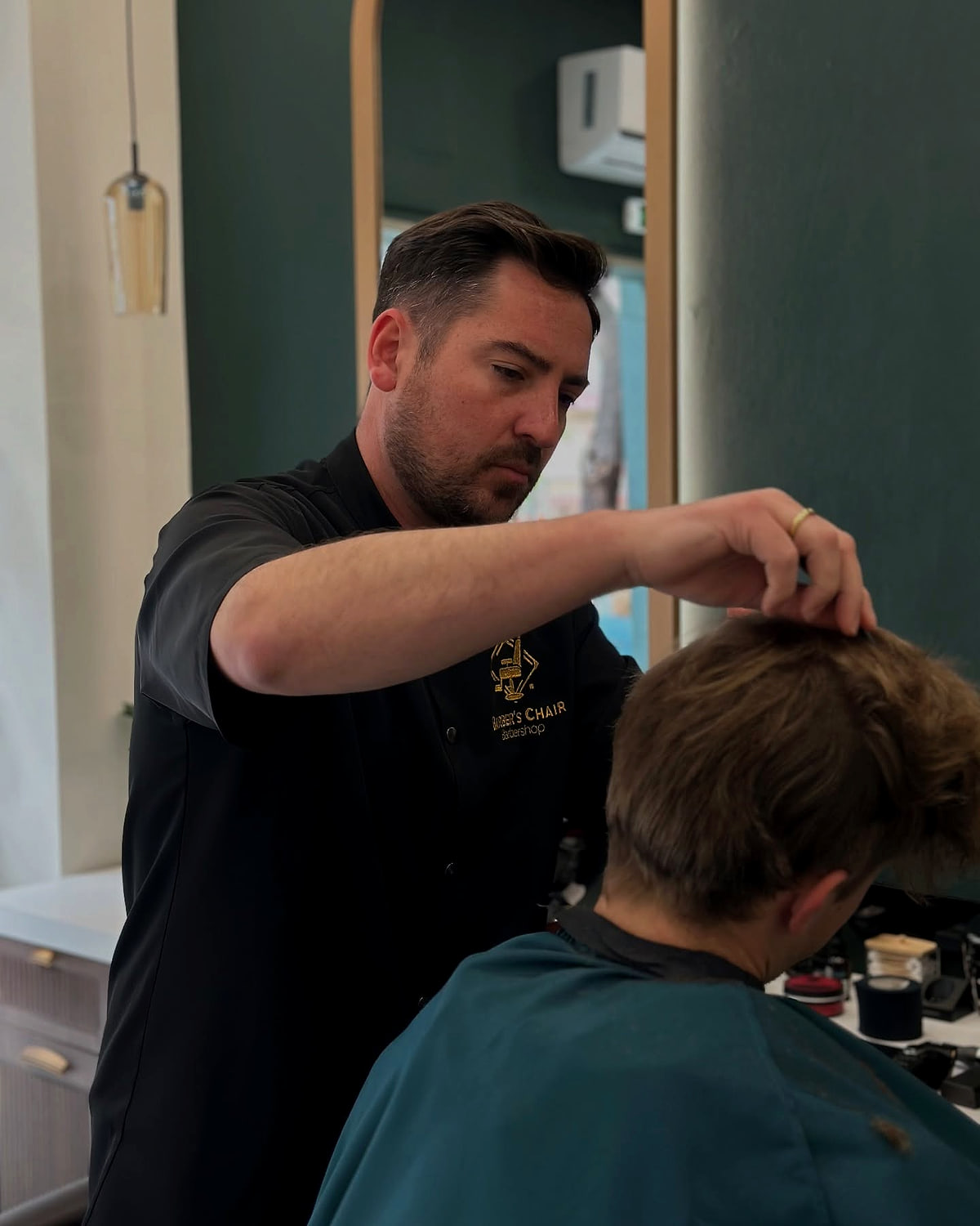 Barber του Barber's Chair εν ώρα εργασίας, κουρεύει ένα παιδί στην καρέκλα